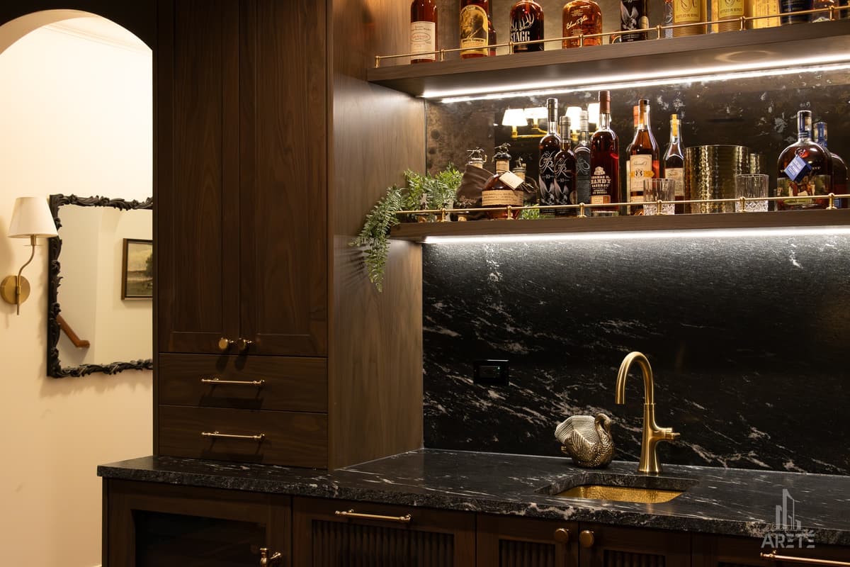 Finished basement wet bar with stone backsplash and brass faucet