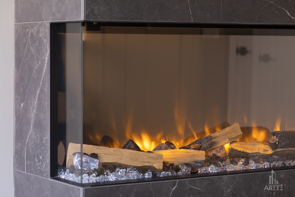 A modern fireplace with glass front, featuring glowing logs and decorative crystals.