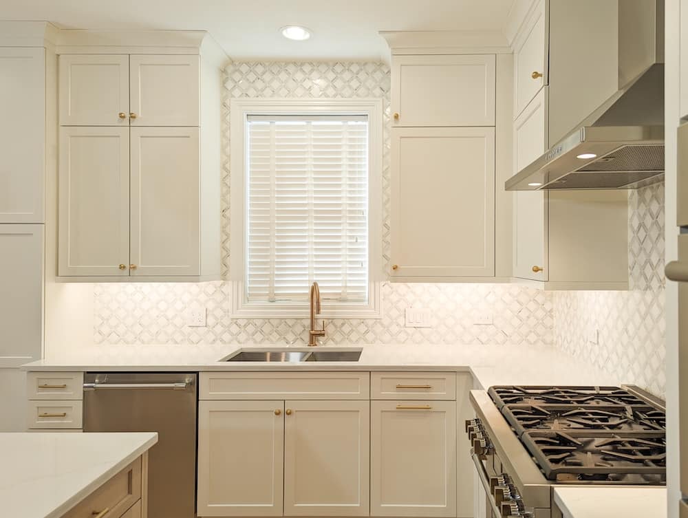 A modern kitchen with white cabinets, a sink, and a patterned backsplash.