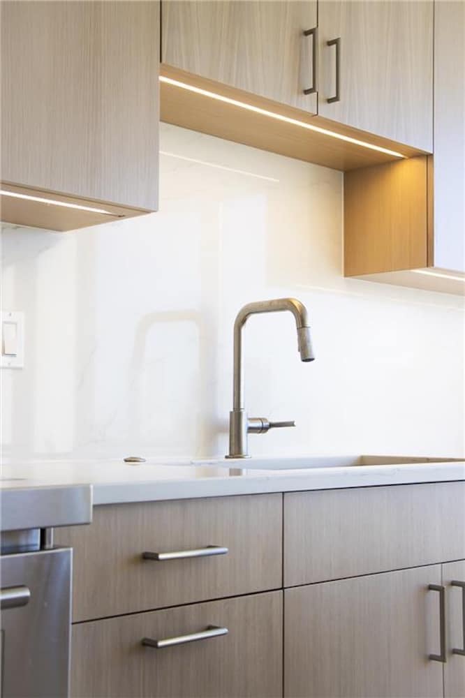 Modern kitchen with light wood cabinets a sleek sink and a marble backsplash - Arete' Modern kitchen with light wood cabinets a sleek sink and a marble backsplash